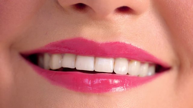 closeup of a female mouth with berry lipgloss smiling Perfect female smile