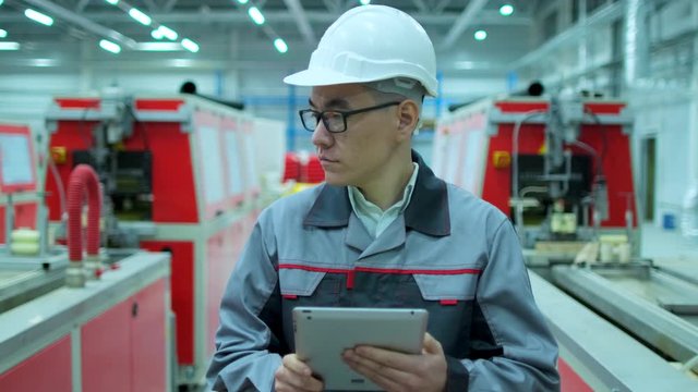Asian, chinese Korean professional male engineer man business people in hard hat working on engineering industrial manufacturing facility using tablet indoors, worker architect inspection. slow-mo 4 K