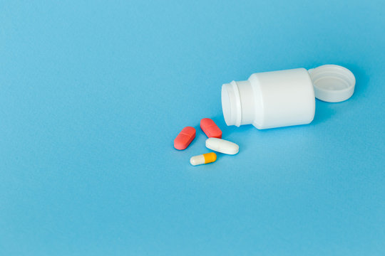 medicines with packaging on a blue background, container, scattered pills isolated on blue background. Copy space.