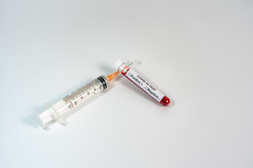 Obraz premium Medical syringe and COVID-19 blood test sample on white background