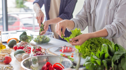 Millennial couple preparing healthy vegetarian salad enjoying process