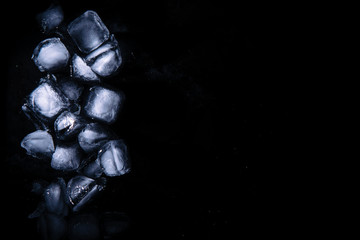 Ice cubes on black cold refreshing background close-up with place for text, top view