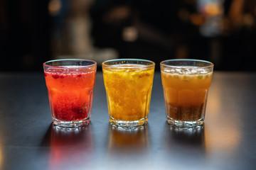 Hot drinks from fruits and berries on a black table against the background of the cafe's interior.