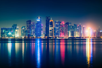 Plakat Night view on the centre of the city Doha, Qatar with many modern luxury building and skyscrapers illuminated with bright lights.