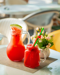 a glass with watermelon juice and a decanter with juice