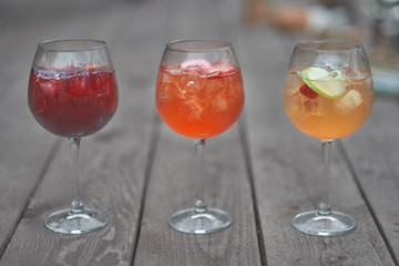 three alcoholic cocktails with fruits on an old wooden table