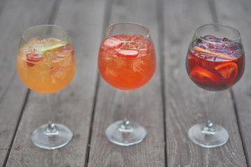 three alcoholic cocktails with fruits on an old wooden table