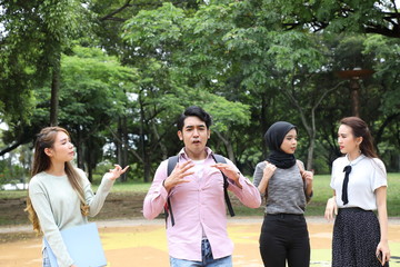 Young asian malay chinese man woman outdoor park walk stand study talk discuss point laptop file book backpack