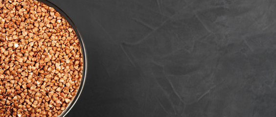 Buckwheat in a glass bowl at the edge of the frame near the copy space on a black abstract...