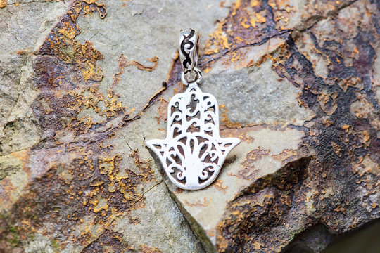 sterling silver metal pendant on natural background in the shape of hamsa, fatima hand