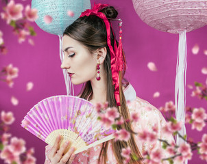 Geisha in pink kimono and with a fan close-up on a purple background and with blurred sakura flowers