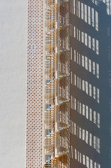 Emergency metal staircase casting its shadow on a neutral-coloured façade. Abstract image