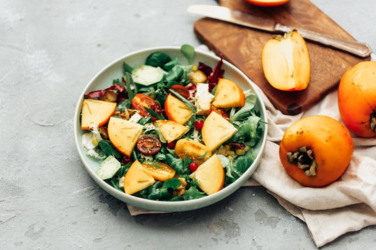 Fresh salad with fruits and greens on white wooden background close up. Healthy food.