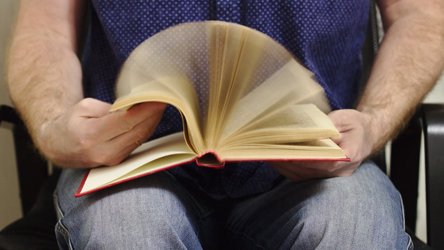 The man quickly flips through the book.