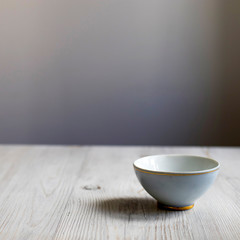 Small blue bowl with a gold border on a wooden surface of the table