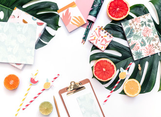 Fototapeta na wymiar Flat lay of minimal workspace, Clip board with fresh summer fruits composed on top of bright green Monstera leaf