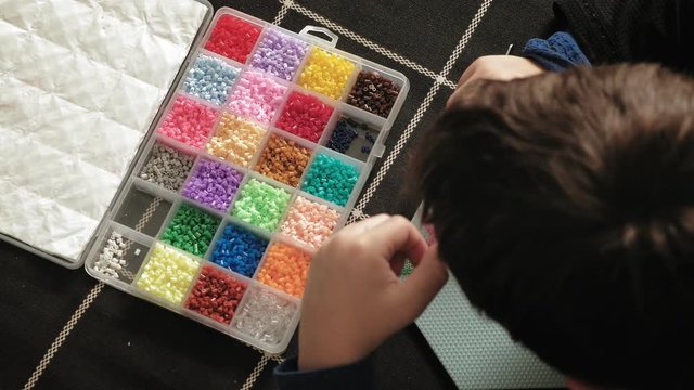 child plays with perler beads. fine motor development