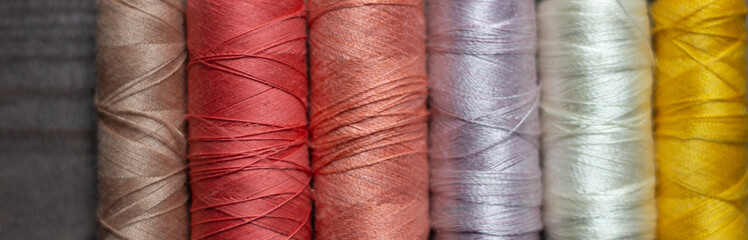Colorful spools of sewing thread close up as background