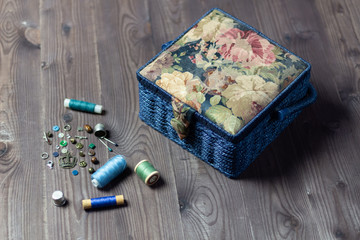 Box for hand made and sewing on brown wooden background with decorative elements, buttons, thpreads