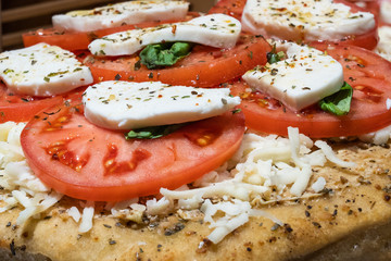 close up of a margherita pizza with fresh tomatoes and mozzarella cheese waiting to be baked