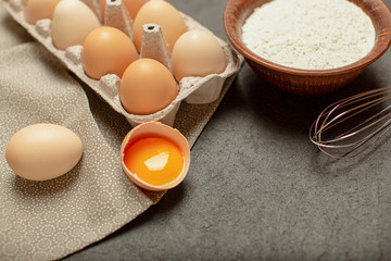 Baking cooking ingredients, flour, eggs and kitchen textile on stone grey background. Top view, copy space