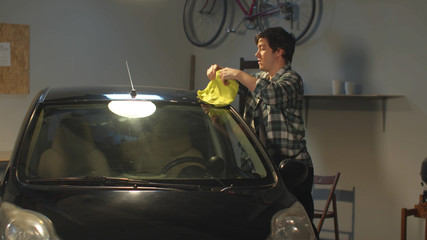The guy washes his car with a rag. Medium shot