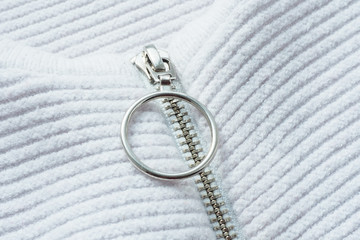 Abstract background and texture of a knitted white jacket with a zipper and a fastener with a metal ring...