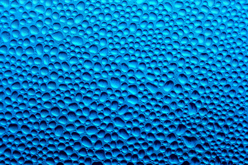 Water droplets on the glass with a colored background. Drops of water
