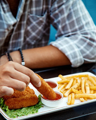 man dipping chicken nugget into sweet chili sauce