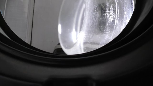 Closing the lid of washing machine, inside out view.