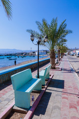 Tadjoura, Djibouti - November 09, 2019: Palms and Boats on the Sea Coastline under Blue sky