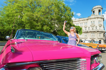 Female tourist photographing Havana streets while passing in the convertible car