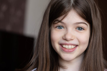 Closeup portrait of a young beautiful smiling brunette girl with big blue eyes. Close-up smile,...