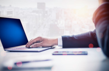Businessman using laptop and smart phone  in office and city background and clipping path of laptop screen.
