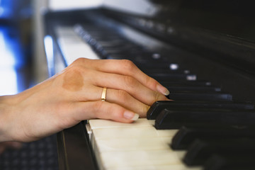 Girls hands on the keyboard of the piano. The girl plays piano,close up piano. Hands on the white keys of the Piano Playing a Melody. Womens Hands on the keyboard, Playing the Notes Melody