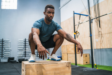 Athletic man doing box jump exercise.