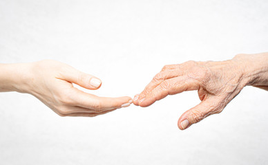 A young hand reaches for an old hand. Help for the elderly concept. - Powered by Adobe