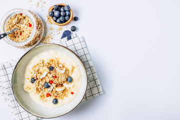 Morning healthy breakfast bowl with yogurt, muesli, blueberry, banana, coconut on the white background. Top view. Flat lay