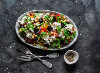 Classic Greek salad with chickpeas on dark background, top view. Vegetarian healthy diet food