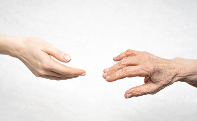 A young hand reaches for an old hand. Help for the elderly concept.