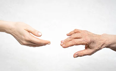 Washable wall murals Old door A young hand reaches for an old hand. Help for the elderly concept.