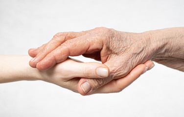 Old wrinkled hand lies on the young hand. Care for old people concept.