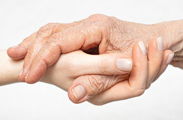 Fototapeta premium Old wrinkled hand lies on the young hand close-up. Helping for the elderly concept.