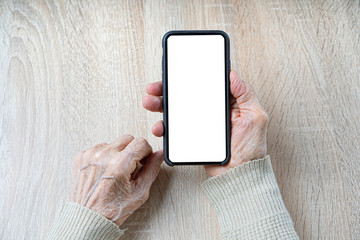 Wrinkled hands of the old woman holds a smartphone with white empty screen for your mockup