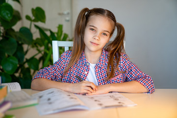schoolgirl in a plaid shirt doing homework