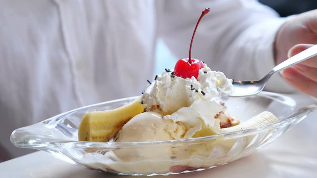 Close-up of ice cream with whipped cream, banana and cherry.