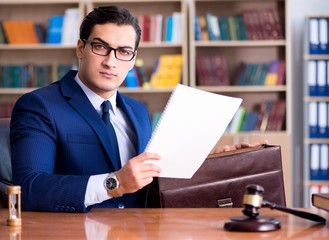 Handsome judge with gavel sitting in courtroom