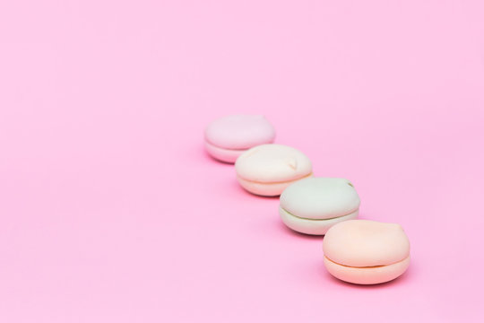 Delicate colored marshmallows on a pink background minimal style. Copy space