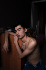 Fototapeta na wymiar portrait of asian guy leaned on bed look out the window