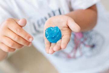 Hand holding a blue slime on a white background. Kid game with sticky slime pulling toy